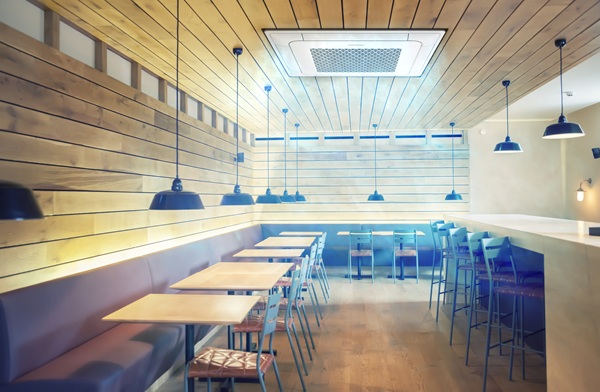 MTF Shop Samsung Klimaanlage Wärmepumpe Österreich | Leistungsstarke 4-Weg WindFree Deckenkassette in einem Gastraum mit Holzdecke. Die Klimatisierung fügt sich perfekt in das moderne Interieur von Café oder Restaurant ein.